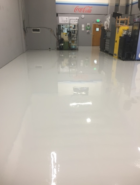 A large room with a white floor and a coca cola sign on the wall.