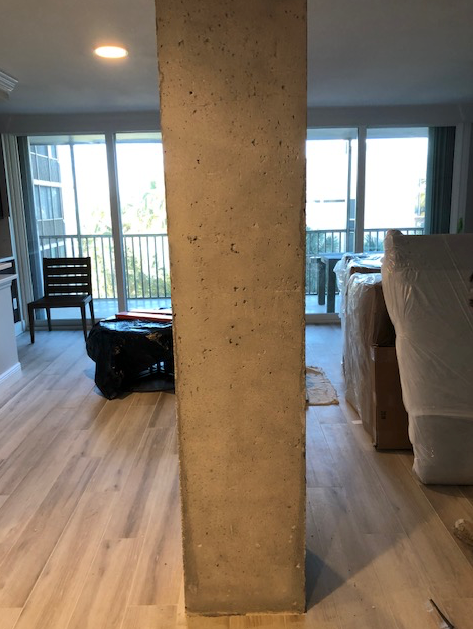 A living room with a concrete column in the middle