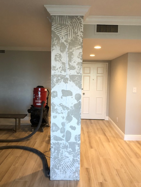 A vacuum cleaner is sitting next to a pillar in a living room.