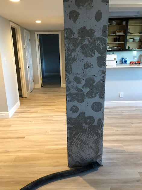 A concrete column in a room with a vacuum hose attached to it.