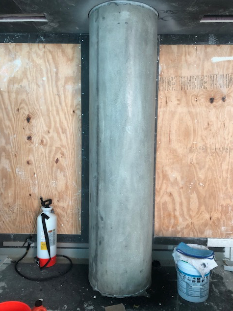 A concrete column with a fire extinguisher next to it