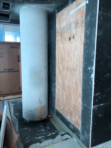 A concrete pillar is sitting next to a wooden wall with boxes in the background