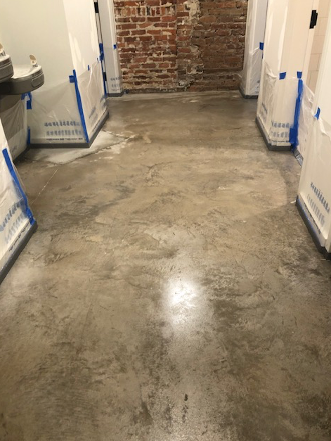 A concrete floor in a room with a brick wall.