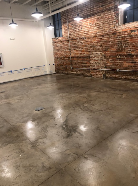 An empty room with a brick wall and a concrete floor.