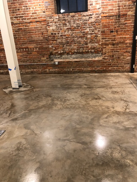 A room with a brick wall and a concrete floor