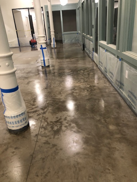 A long hallway with columns and a shiny concrete floor.