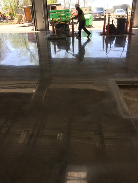 A man is standing on a shiny concrete floor in a garage.