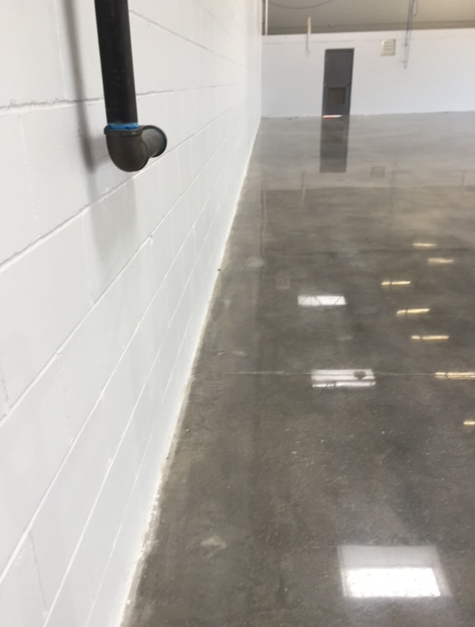 A warehouse with a concrete floor and white brick walls.