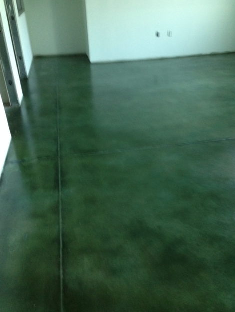 A green concrete floor in a room with white walls.