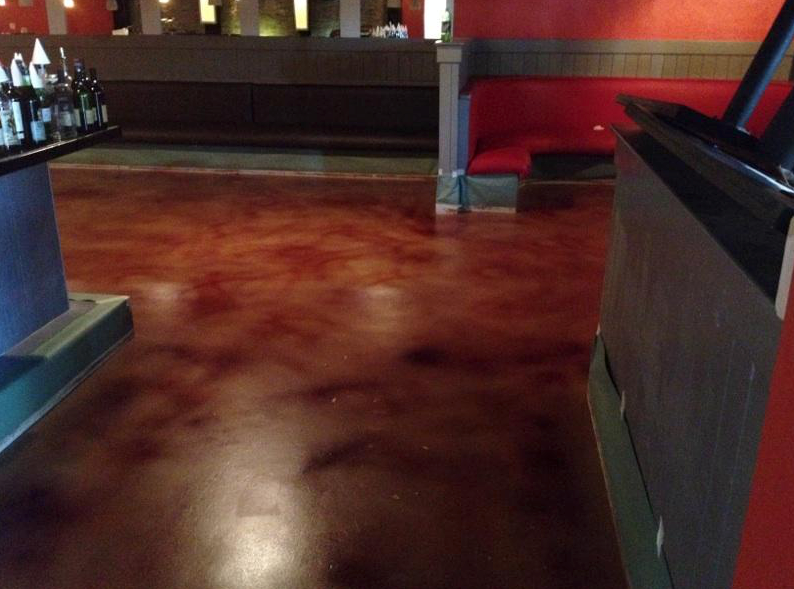 A restaurant with a red couch and a dark colored floor