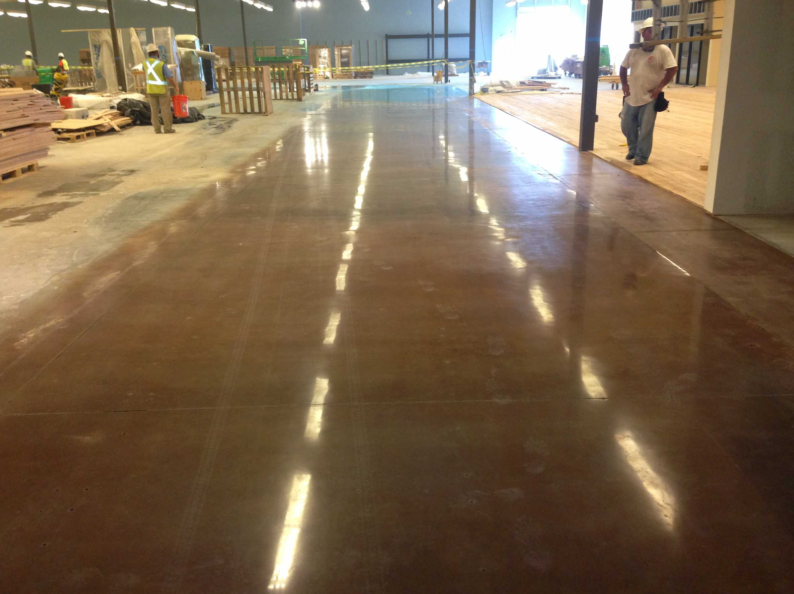 A man is walking on a shiny concrete floor in a warehouse.