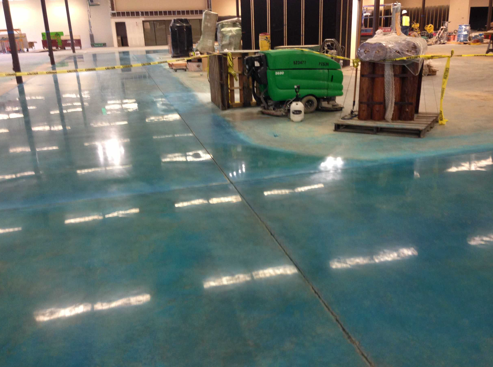 A green machine is cleaning the floor of a building.