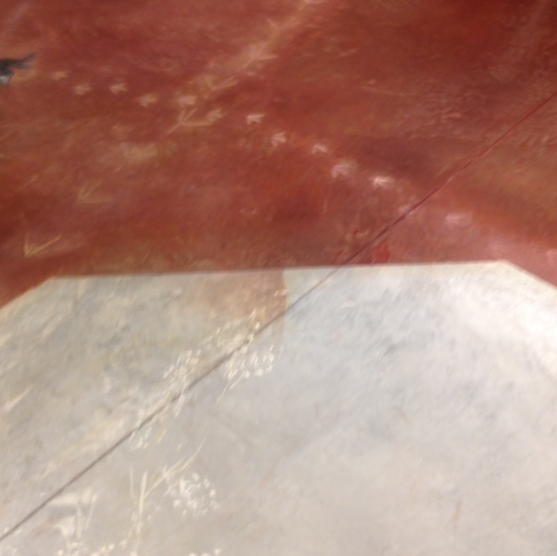 A close up of a concrete floor with a red stain on it.