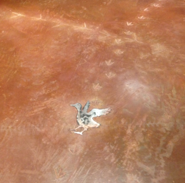 A small statue of a bird is on a brown surface