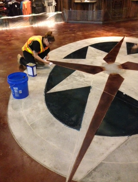 A woman is kneeling down in front of a compass on the floor