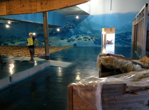 A man is standing in a room with a large painting on the wall.