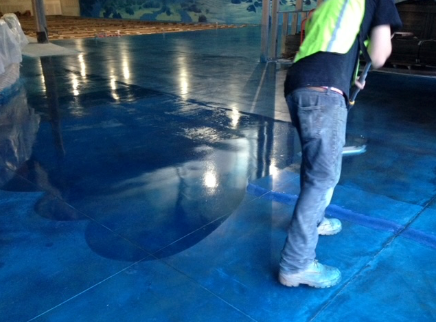 A man is standing on a blue concrete floor.