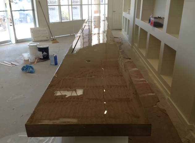 A long wooden table in a room with shelves and a mop