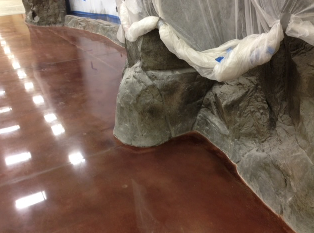 A shiny concrete floor with a rock in the background.