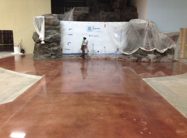 A man is standing on a shiny concrete floor in a room.