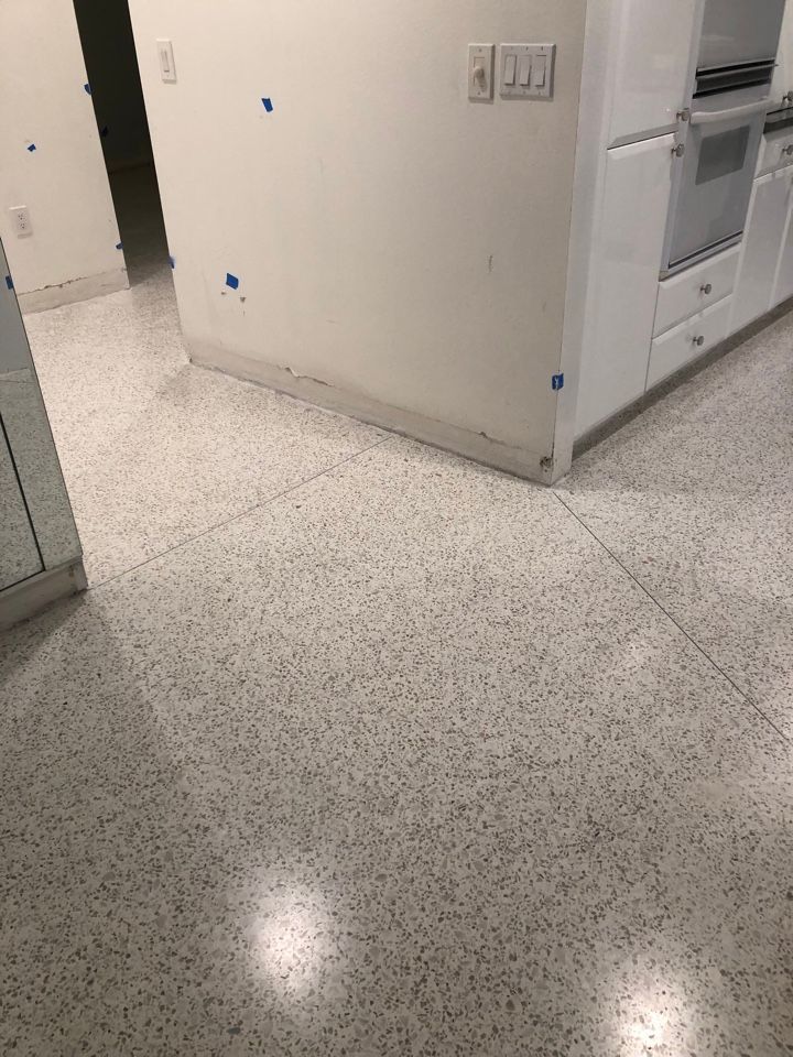 A kitchen with a white tile floor and white cabinets.