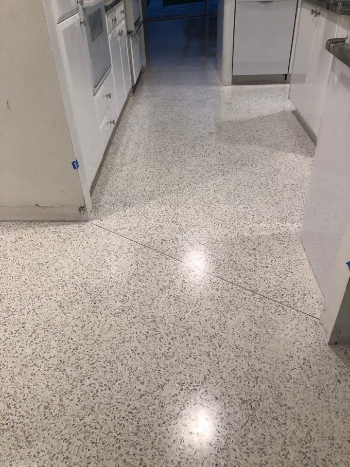 A kitchen with a white tile floor and white cabinets.