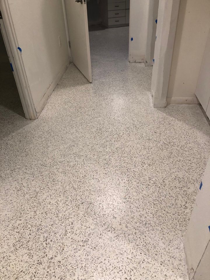 A hallway with a white tile floor and white cabinets.