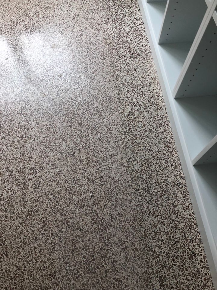 A close up of a carpeted floor next to shelves in a room.