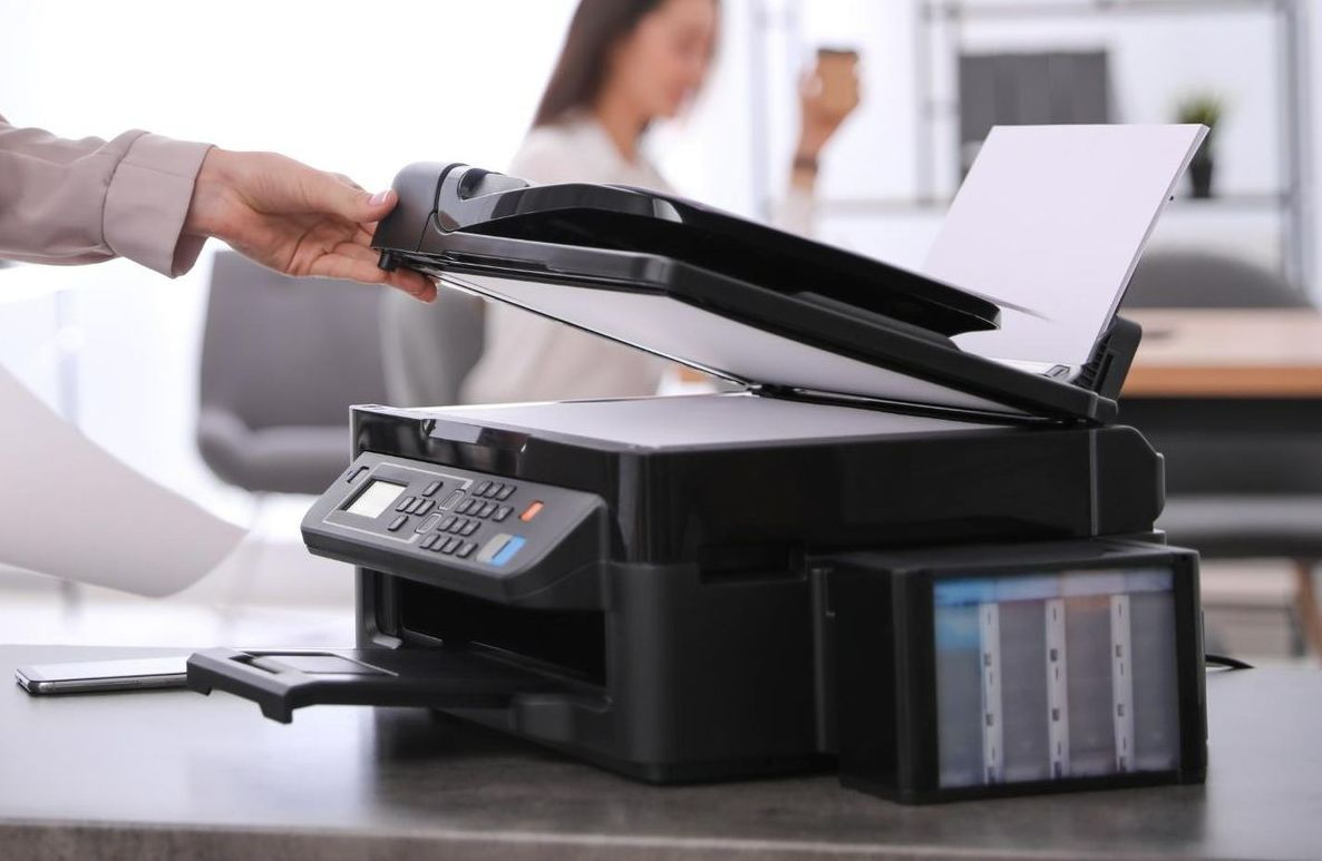 A Person Is Putting a Piece of Paper Into a Printer — Ink n' Toner Forster in Forster, NSW