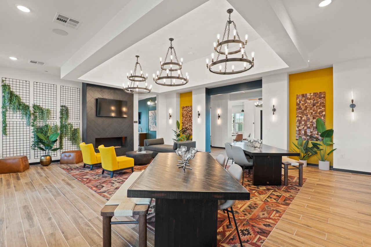 Modern multifamily community lounge with seating, plants, and a fireplace.