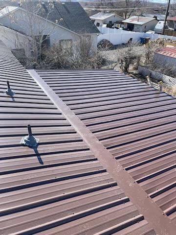 Brown corrugated metal roof on a building, with a flat metal seam down the middle.