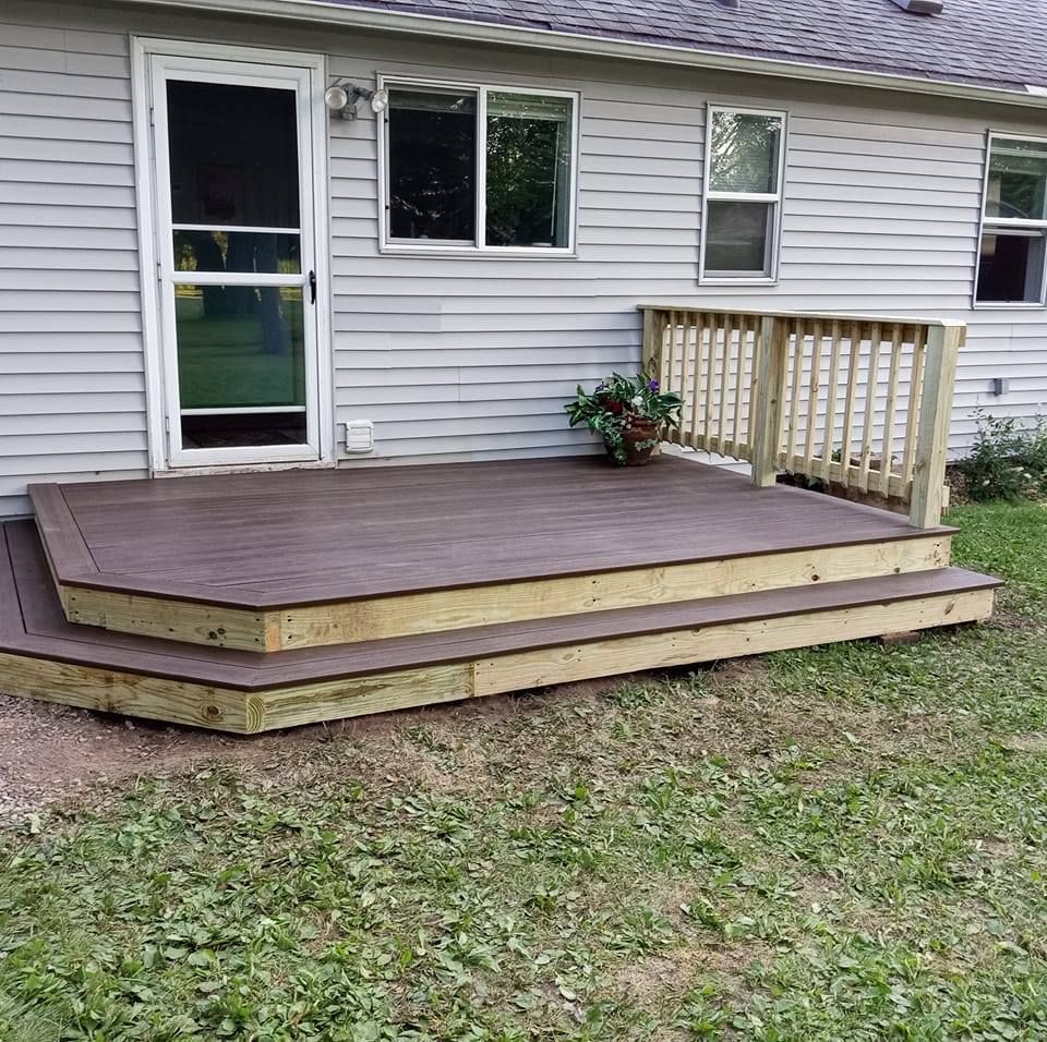 Small, two-step deck with brown decking, attached to a gray house. Has a railing and a door.