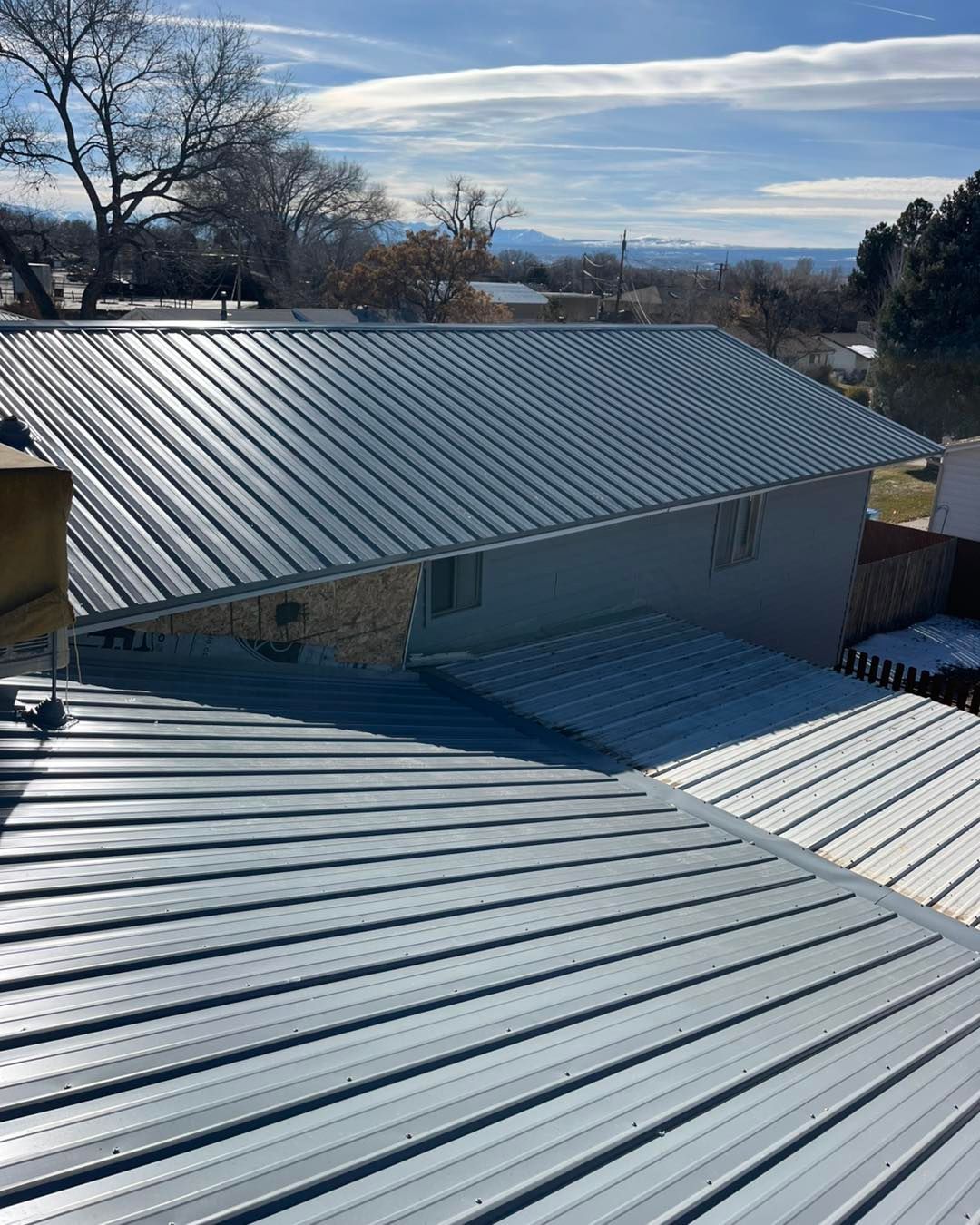 Metal roofs of a building under a bright blue sky.