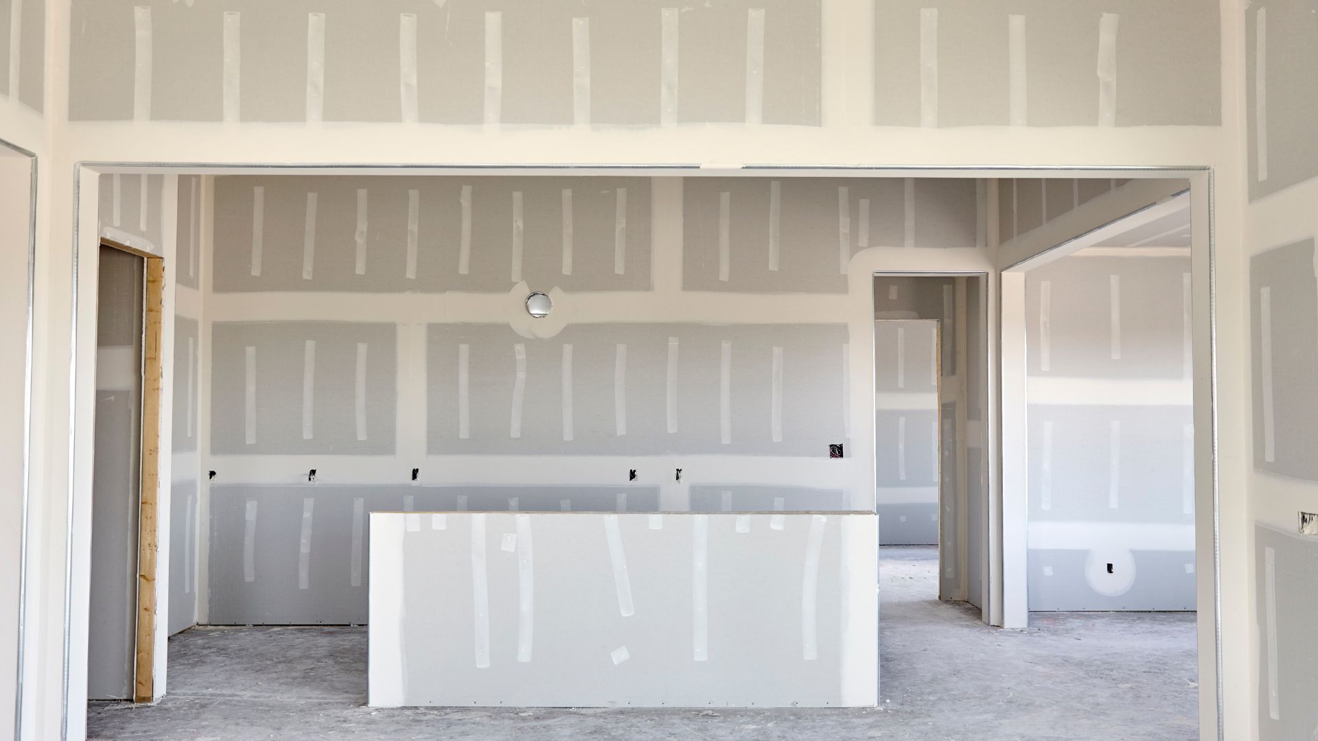 Interior view of a room under construction with exposed drywall walls and ceiling.