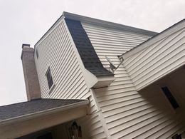 White house exterior with dark roof and brick chimney.