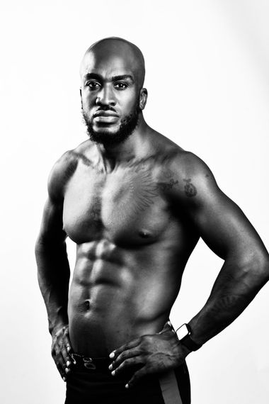 Muscular person, shirtless, hands on hips, gazing at the camera. Black and white photo.