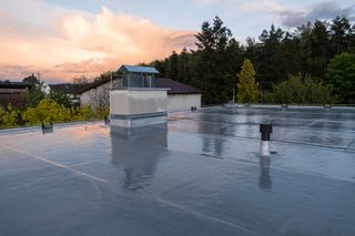 A roof with a chimney on top of it and trees in the background.