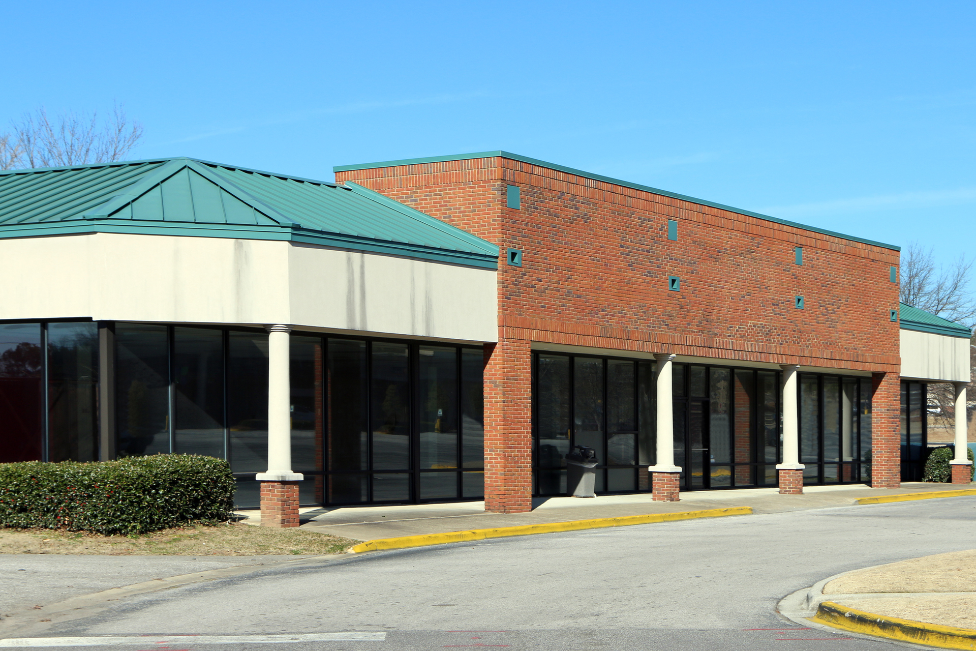 A brick building with a green roof and a lot of windows