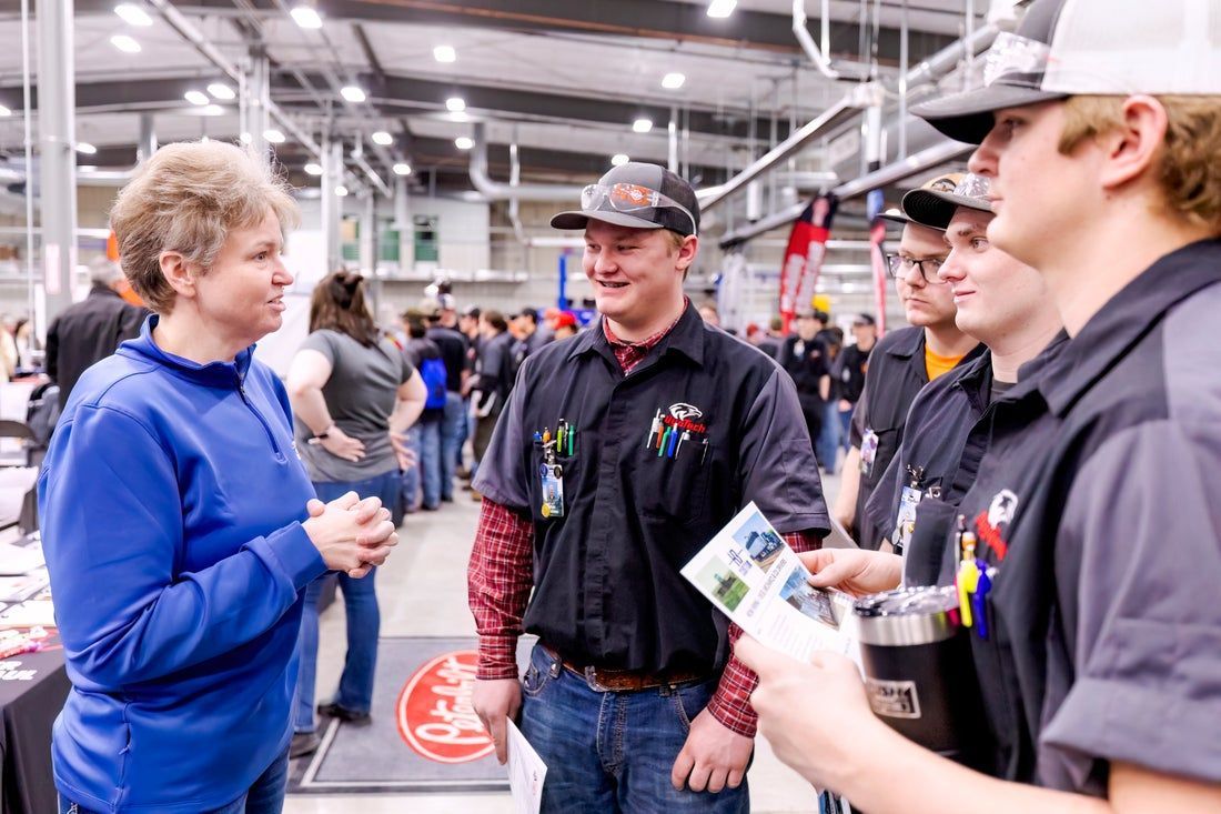 A group of people are standing at a WyoTech Career Fair talking to each other.