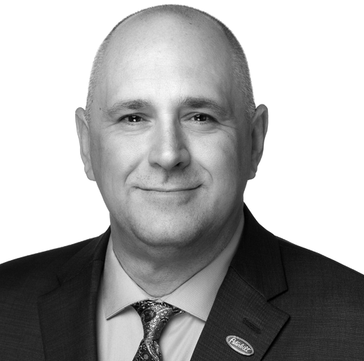 A man wearing headphones and a suit is smiling in a black and white photo.