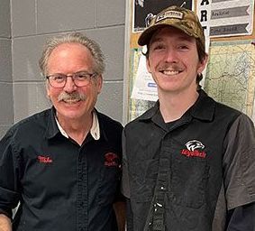 Two men are standing next to each other and smiling for the camera.