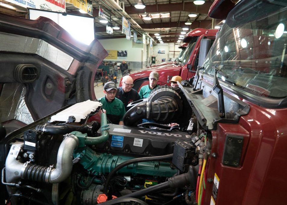 A group of men are working on a volvo truck in a garage.