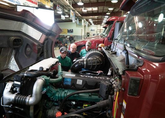 A group of students and instructor are working on a Volvo truck at WyoTech.