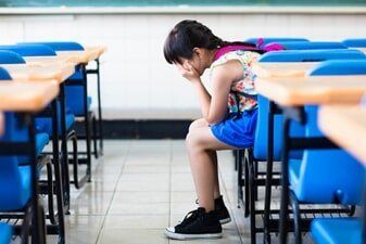 Sad girl sitting and thinking in the classroom — Mental Health Condition Treatment in Pittsburgh, PA