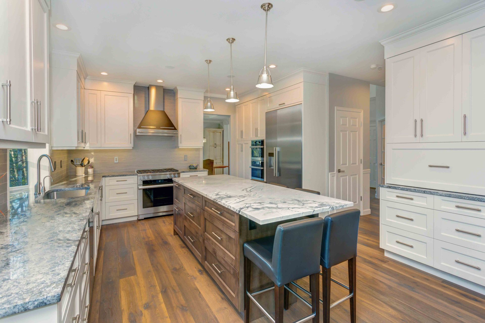 Modern kitchen with marble countertops, stainless steel appliances, and wood flooring decor.