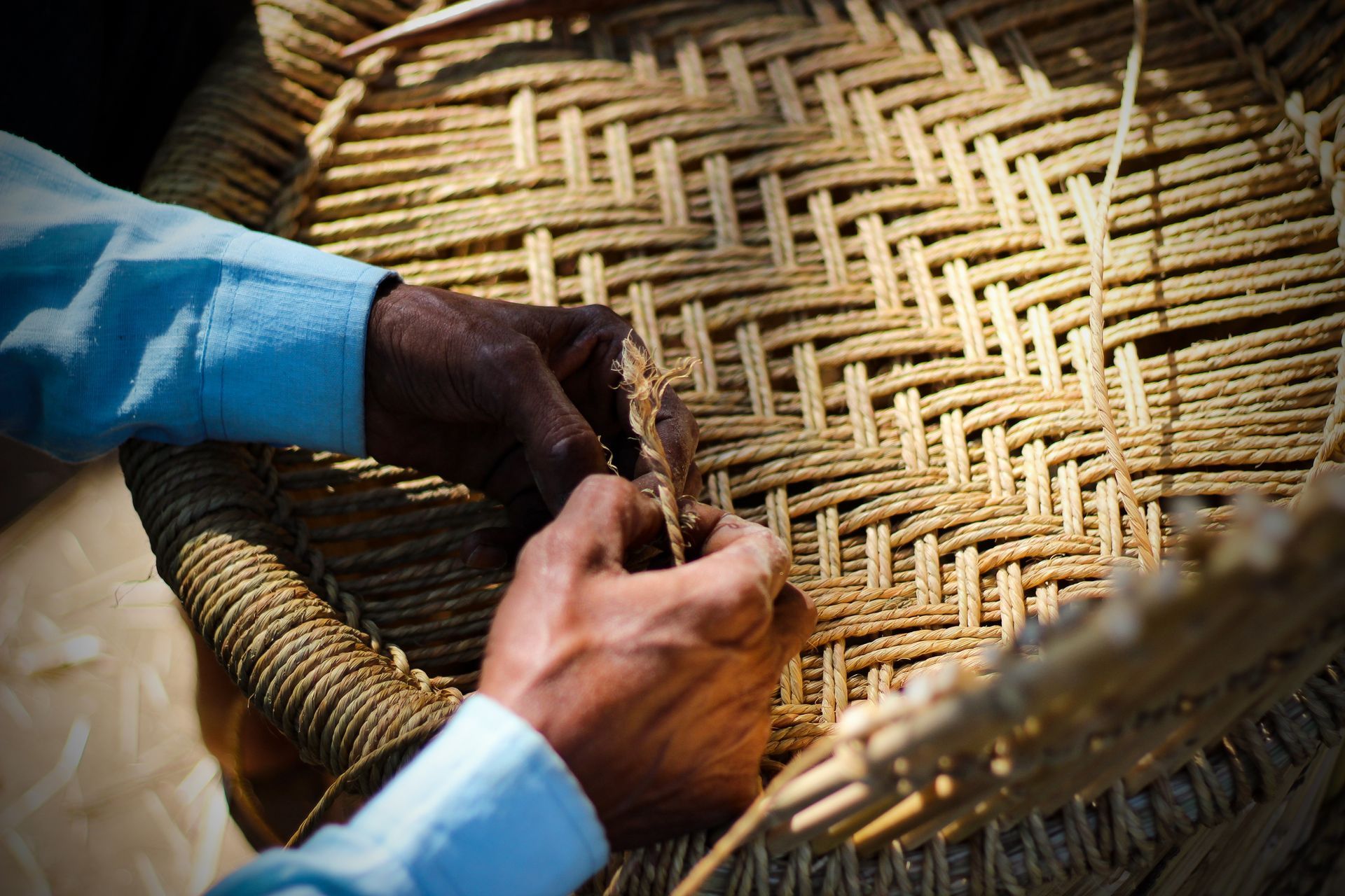 Skilled craftsman working manually a detailed bamboo wood armchair with his fingers and tools Skilled craftsman working manually a detailed bamboo wood armchair with his fingers and tools