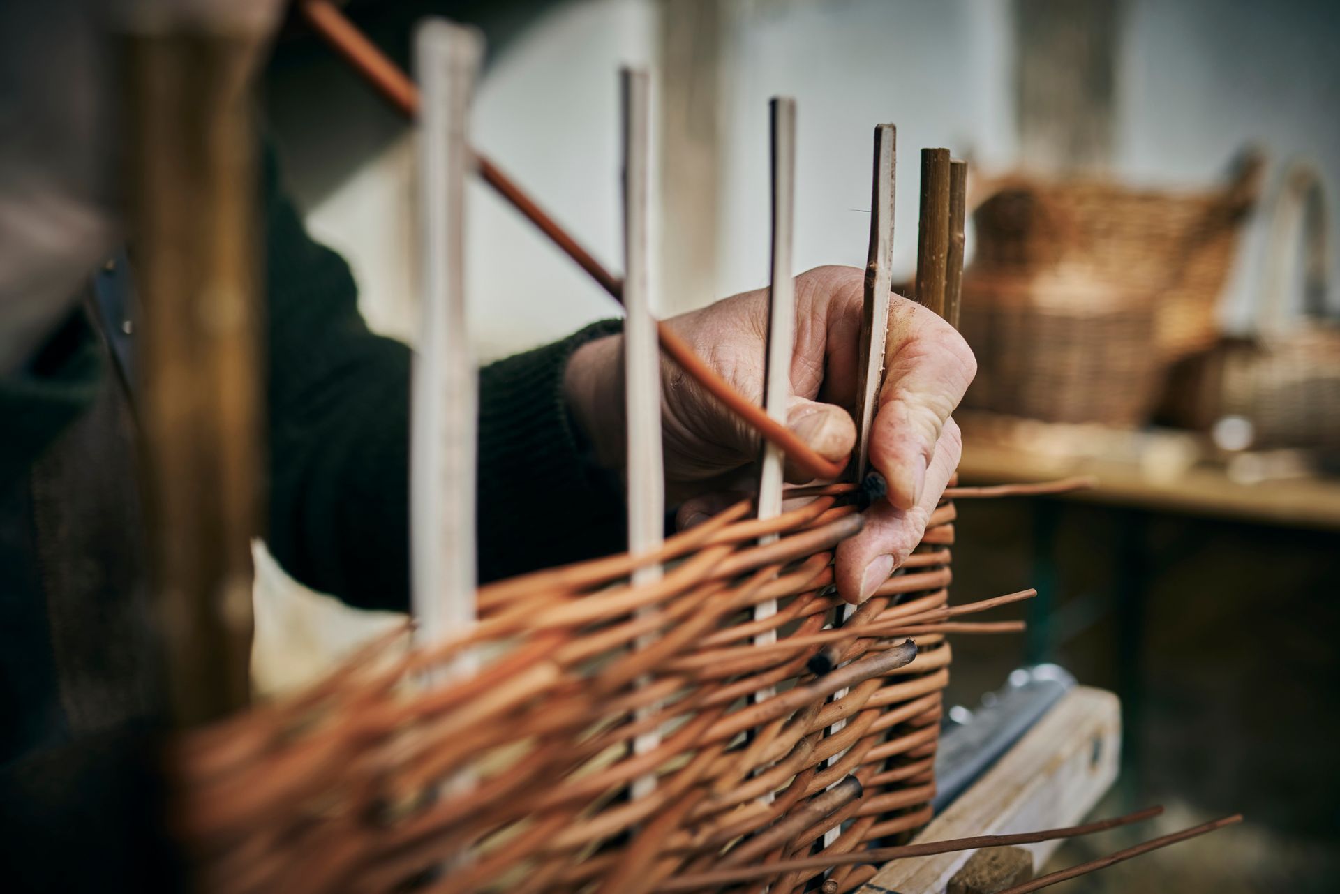 Close-up of basket maker weaving a basket in his workshop.