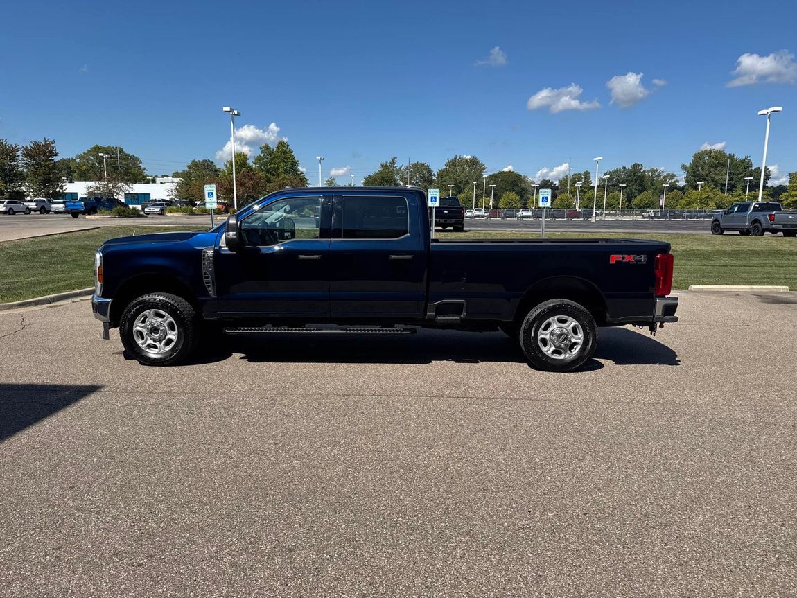 Dark blue pickup truck parked on pavement on a sunny day.