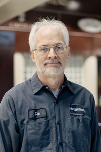 Woman with pink hair wearing a pink polo shirt, smiling in front of a Ford dealership logo.