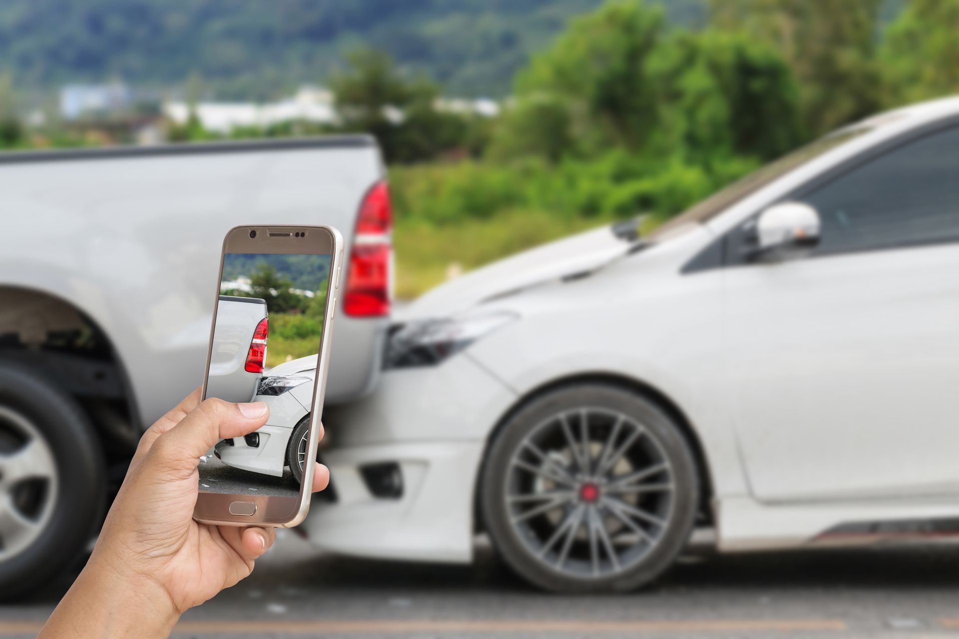 Person taking a photo of a car accident involving a white car and truck.